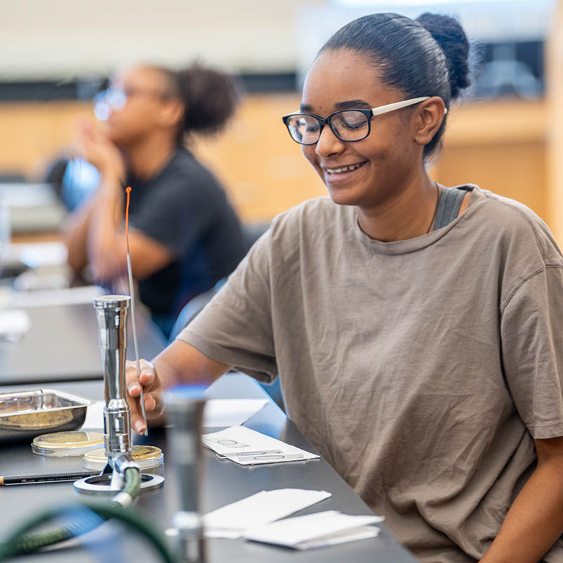 Student using bunsen burner in lab