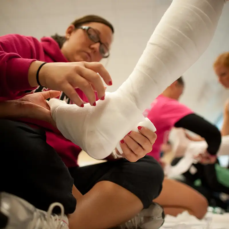 Student wrapping up a foot with gauze during a podiatry lab