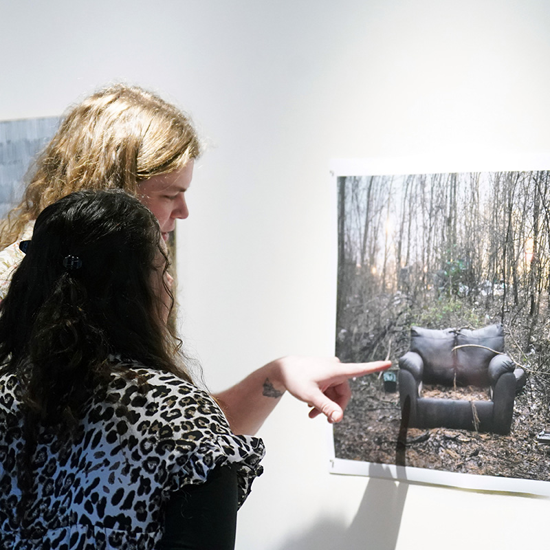 Two people are viewing an art piece on display in a gallery.