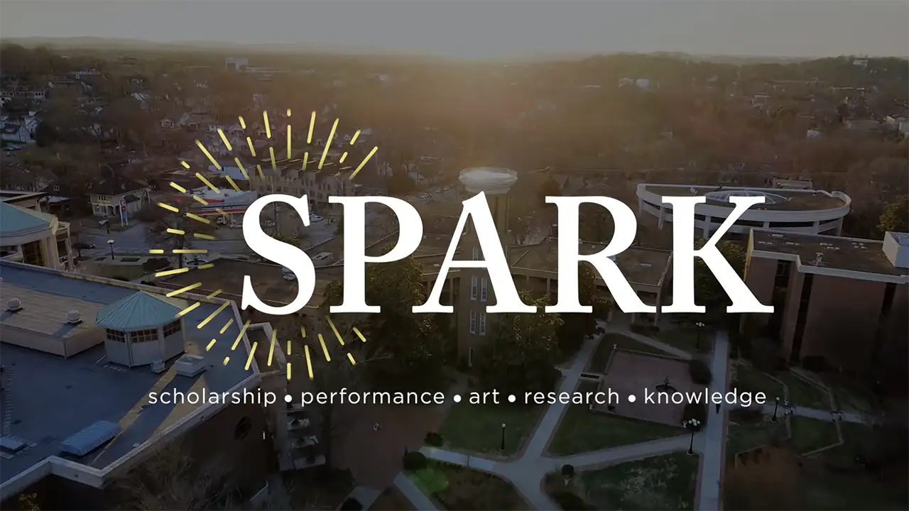 Aerial view of Belmont University’s campus at sunset with the word “SPARK” overlaid and the tagline “scholarship • performance • art • research • knowledge.”