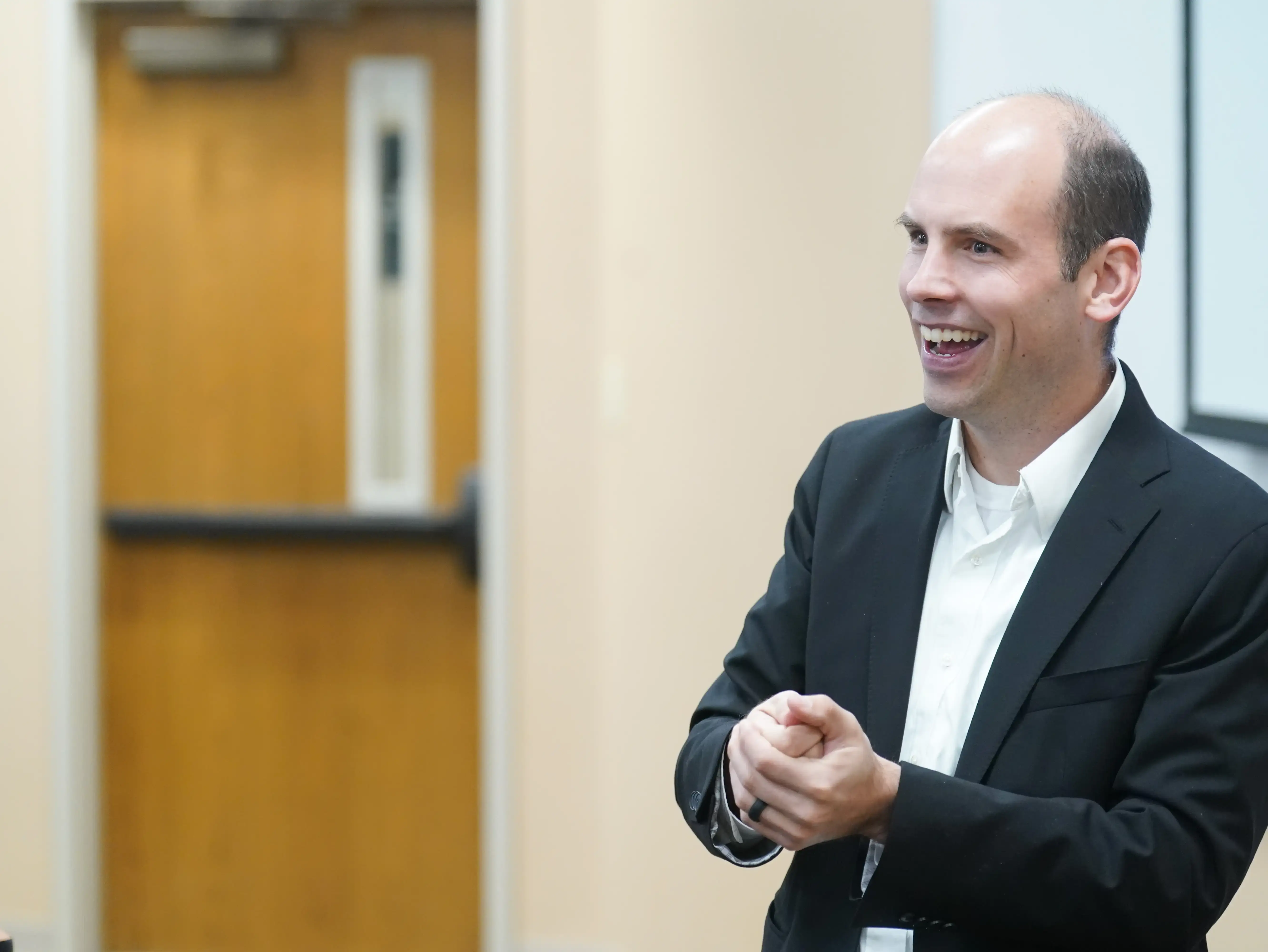 Professor smiling and engaging with an audience in a classroom setting