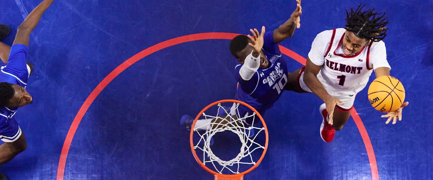 An overhead view of a basketball goal and players reaching for the basketball