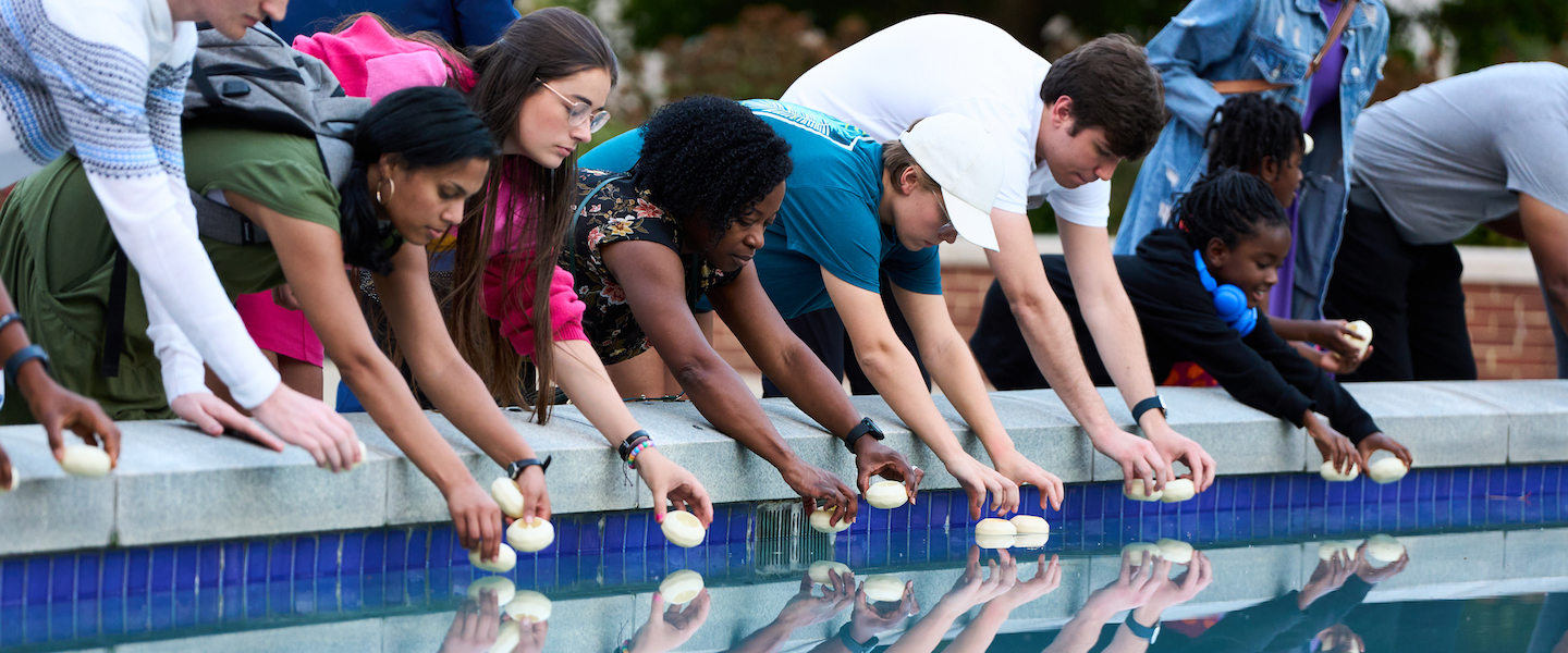 Students, faculty and staff place candle in Freedom Plaza fountain