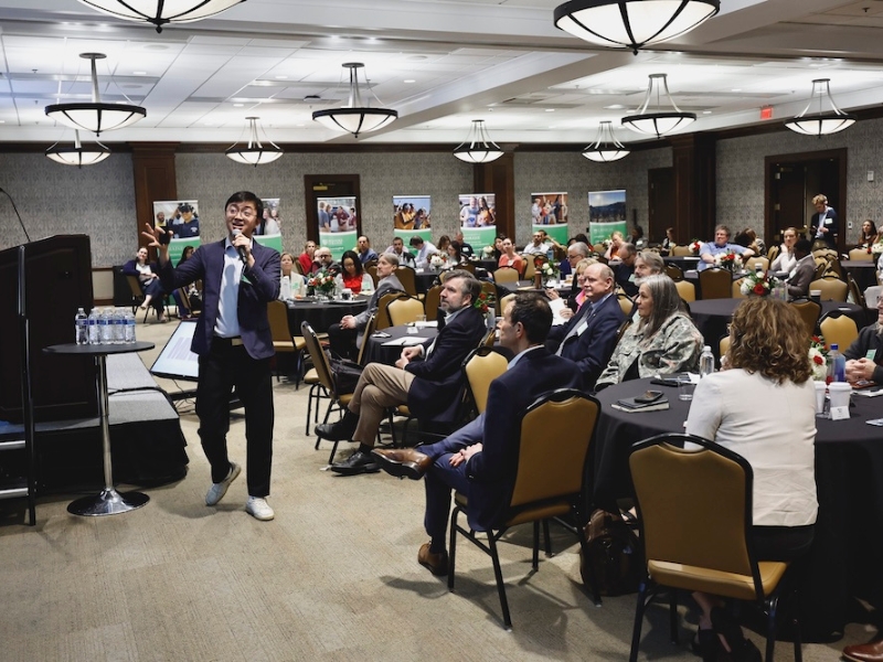 LearningWell Conference attendees; presenter speaking, gesturing with hand in front of crowd