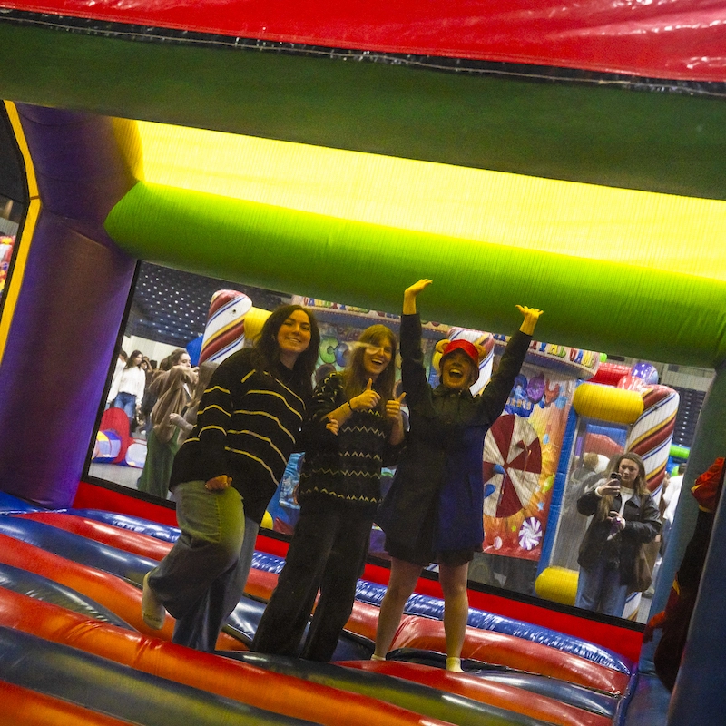 Three students jumping in bounce house