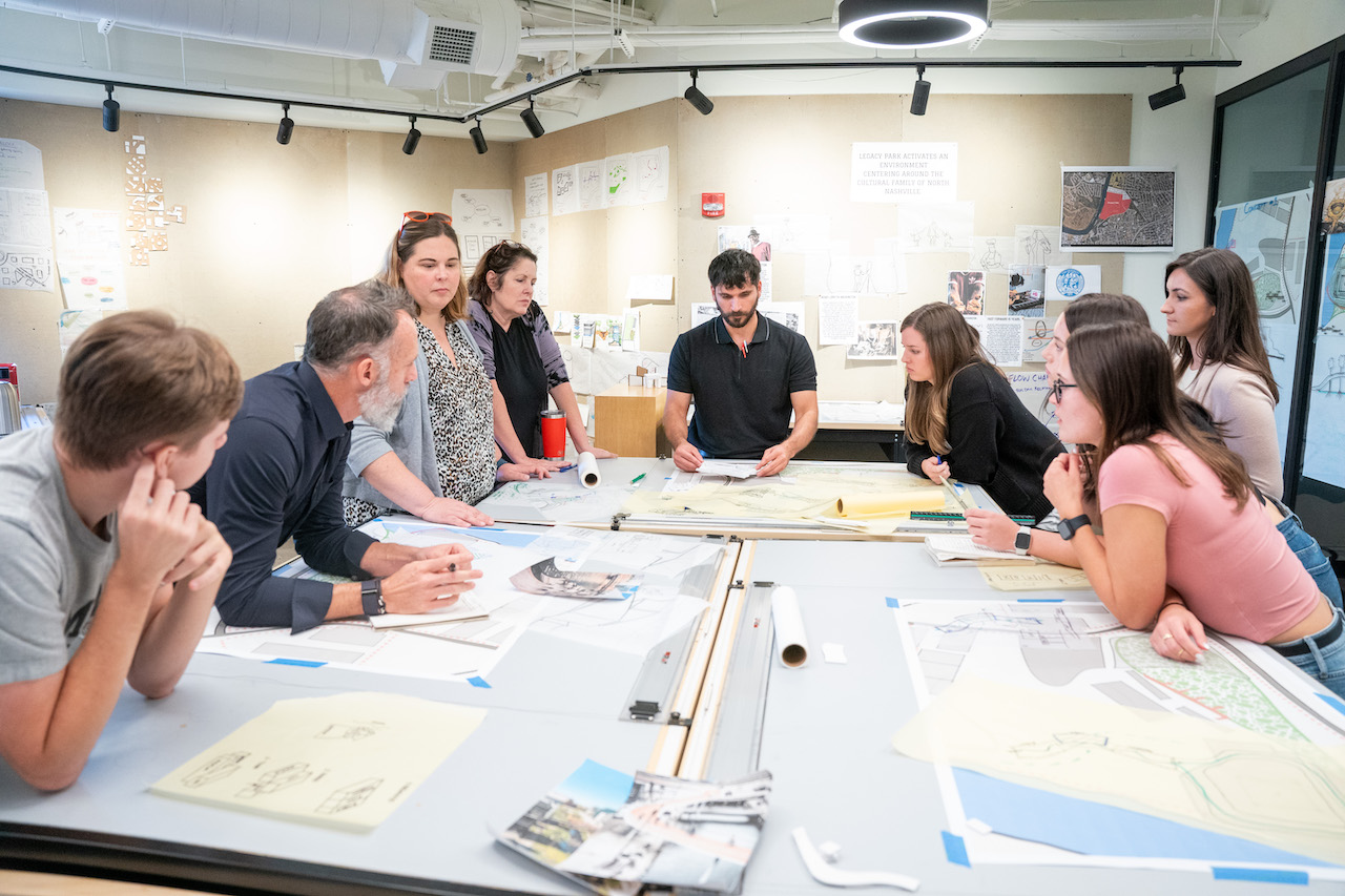 Students around a table learning from professionals during a design workshop