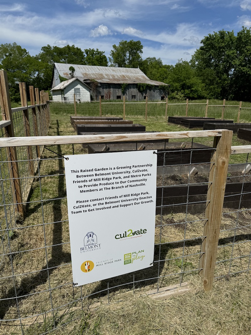 Sign for Belmont's community garden at Mill Ridge Park with The Barn in the far background