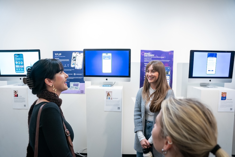 gallery attendees talk with a student about her project