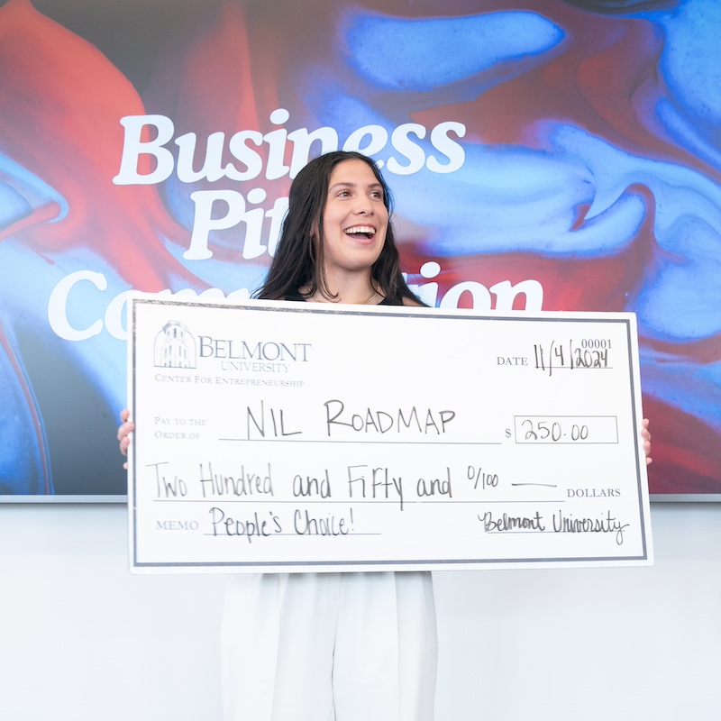 female student holding a giant check worth $250 made out to her company NIL Roadmap