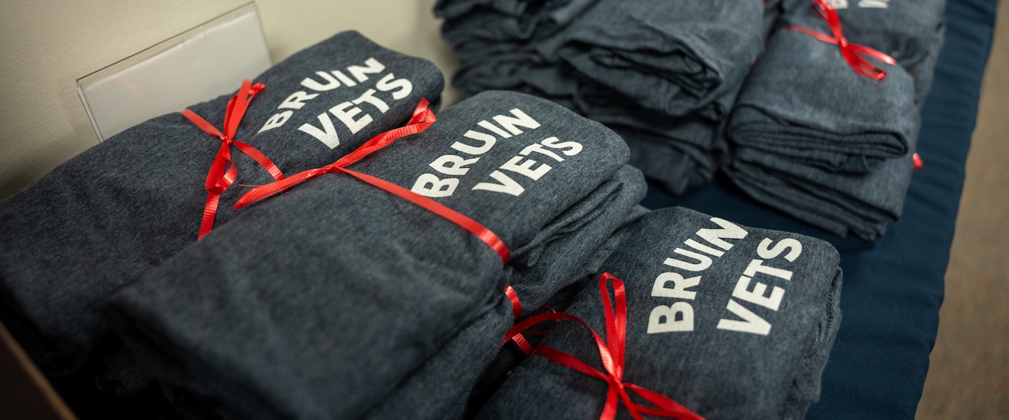 veterans week 2024 shirts stacked with a red ribbon on a table