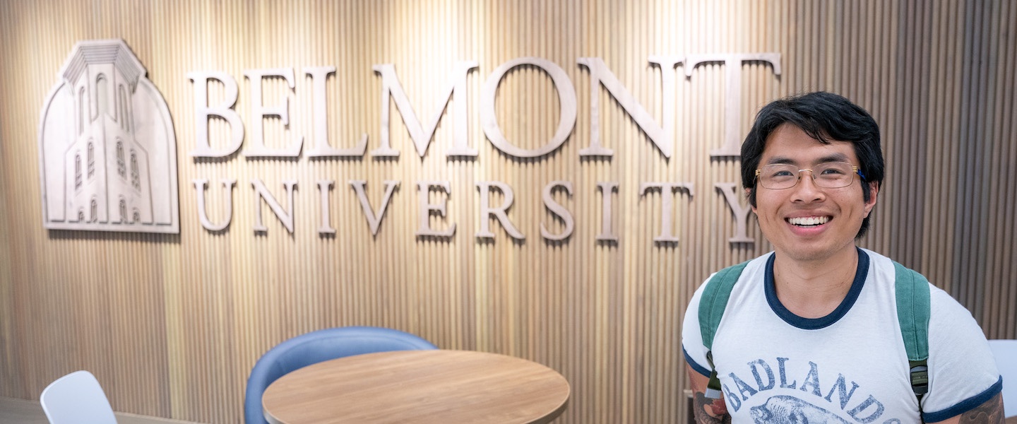 Isaac Wetzel, Global Honors Student, smiles in front of Belmont University sign