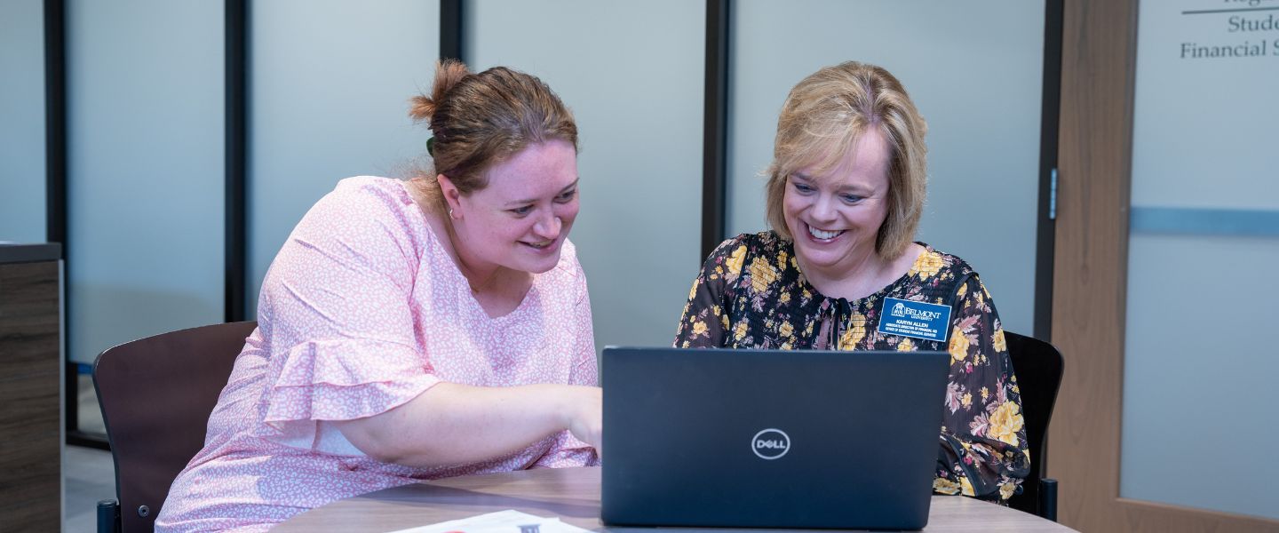 Two people sitting down in front of a laptop