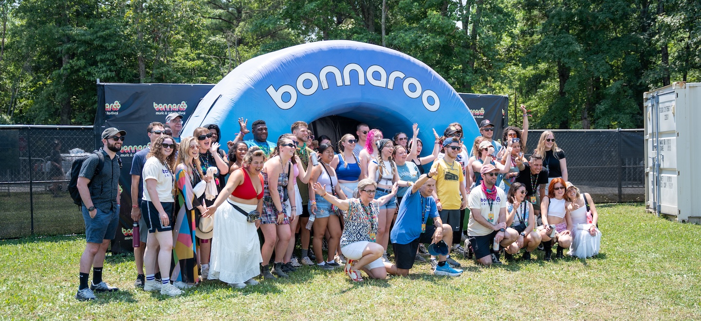 2024 bonnaroo university class poses for a group photo in front of an inflatable arch that reads "Bonnaroo"