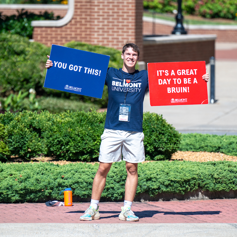 Male student holding a sign that says "You got this" and "It's a great day to be a Bruin."