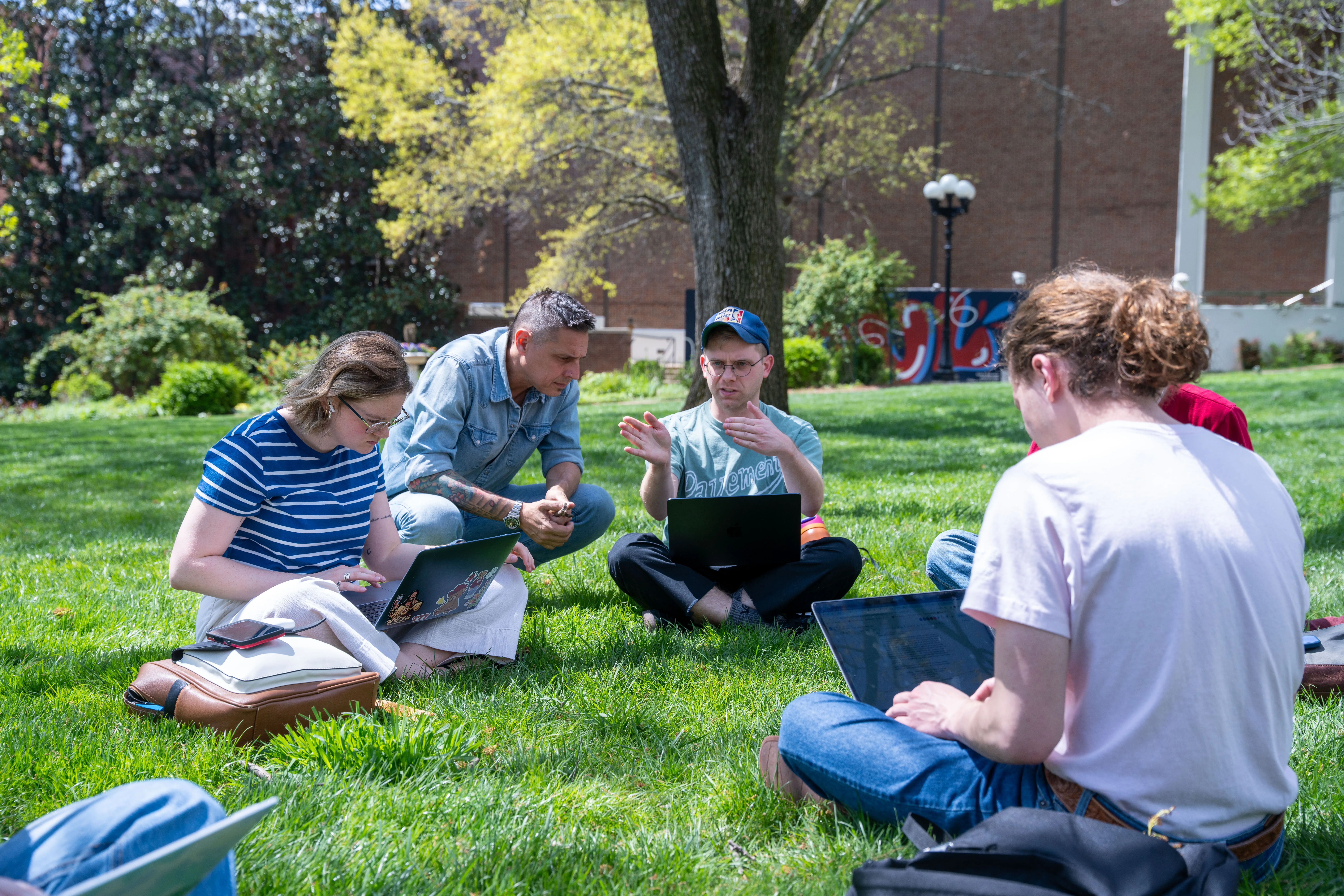 Professor interacting with student on the lawn 