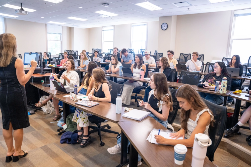 Students sitting in a classroom interacting with a lecture.