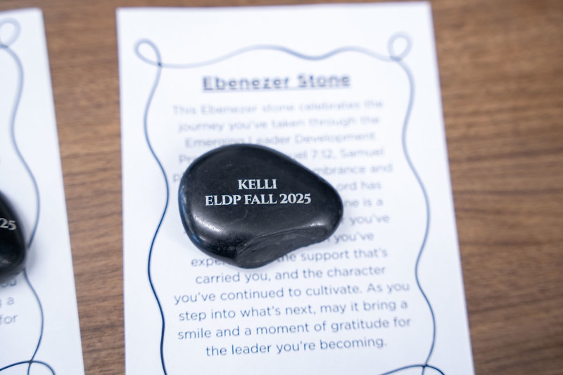 A black stone engraved with “Kelli, ELDP Fall 2025” resting on a brochure explaining the meaning of the Ebenezer Stone. 