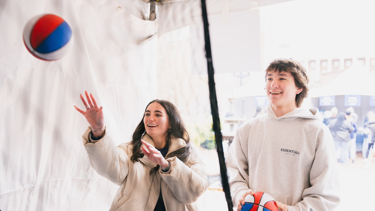 two students playing arcade basketball