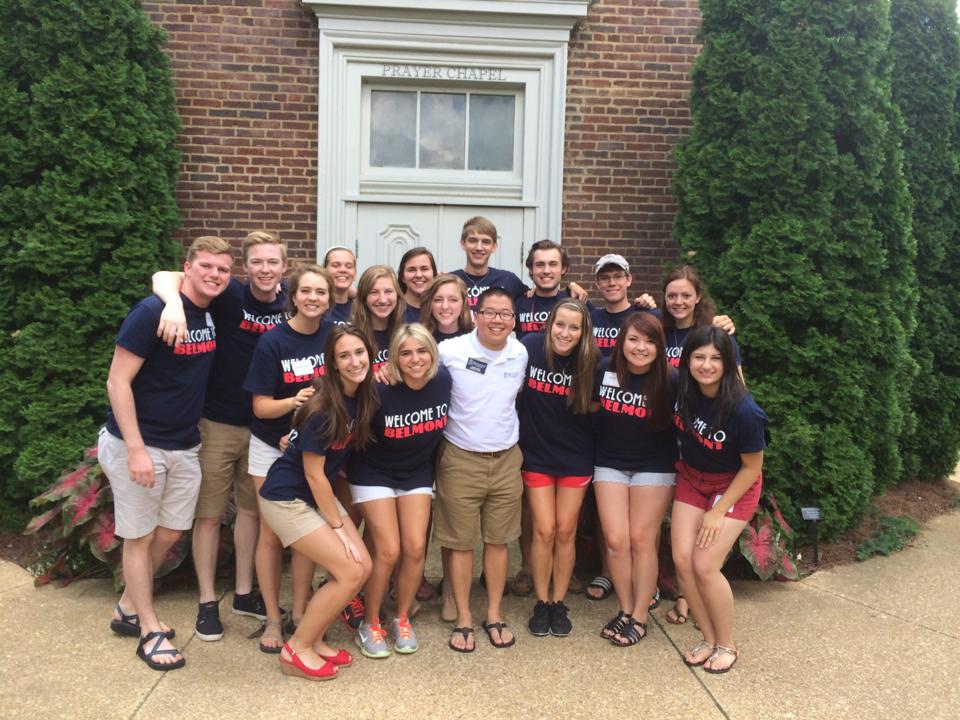 A group of students wearing matching navy 'Welcome to Belmont' t-shirts pose together in front of the Prayer Chapel entrance