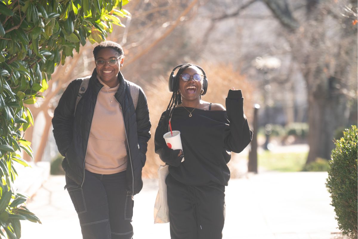 Two students wave while walking through Belmont's campus