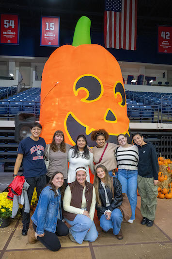 Group of students pose in front of giant pumpkin blow up