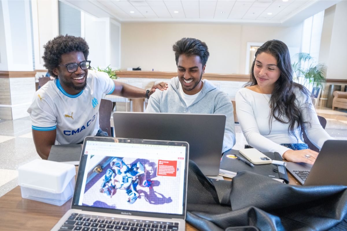 Three students sit around a table