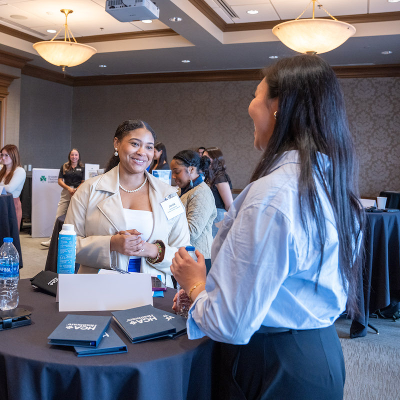 Two women speaking at a standing table