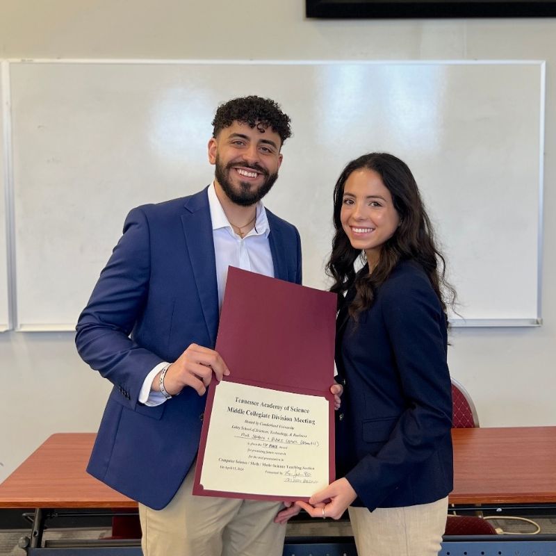 Two students hold up an award