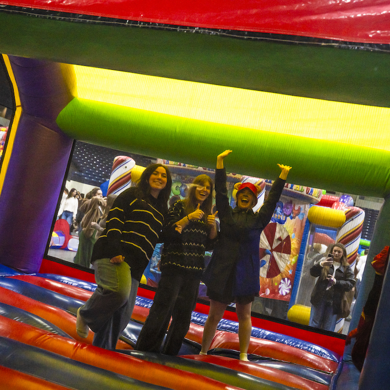 Three students jumping in bounce house