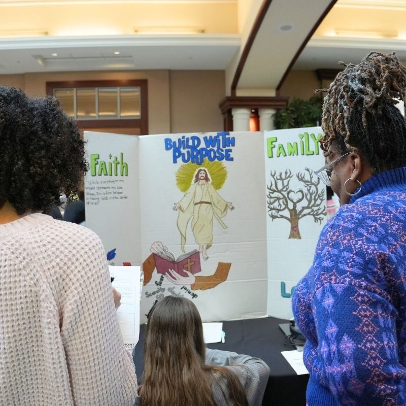 Two women view a project at the What's Your Why Journey Showcase