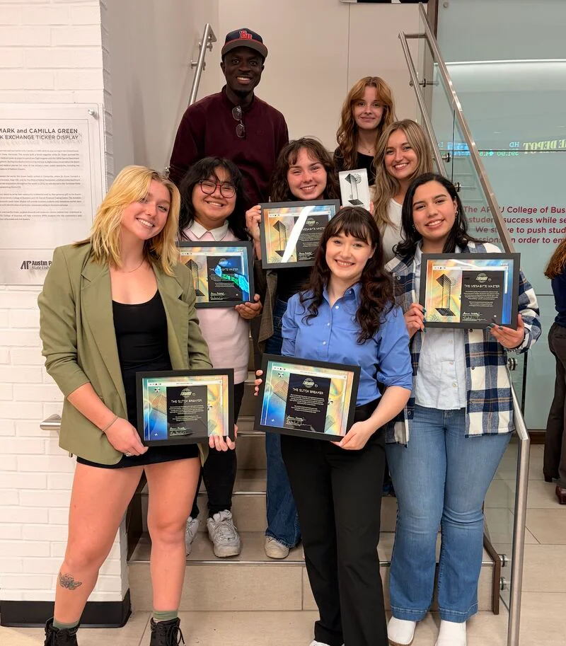 Design students staggered on steps while holding awards.