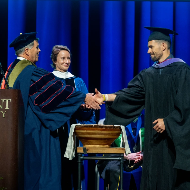 Two professors shaking hands on stage
