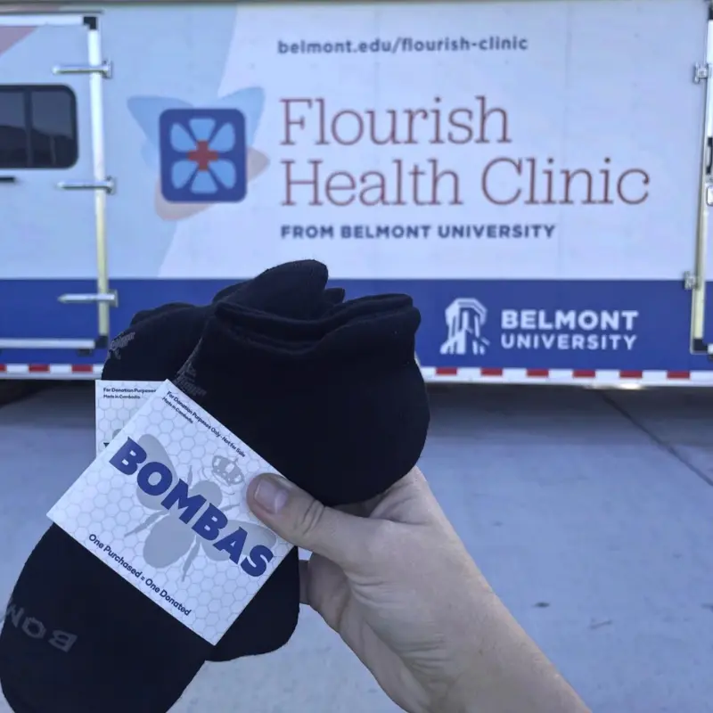 Bombas socks being held up in front of the Flourish mobile clinic 