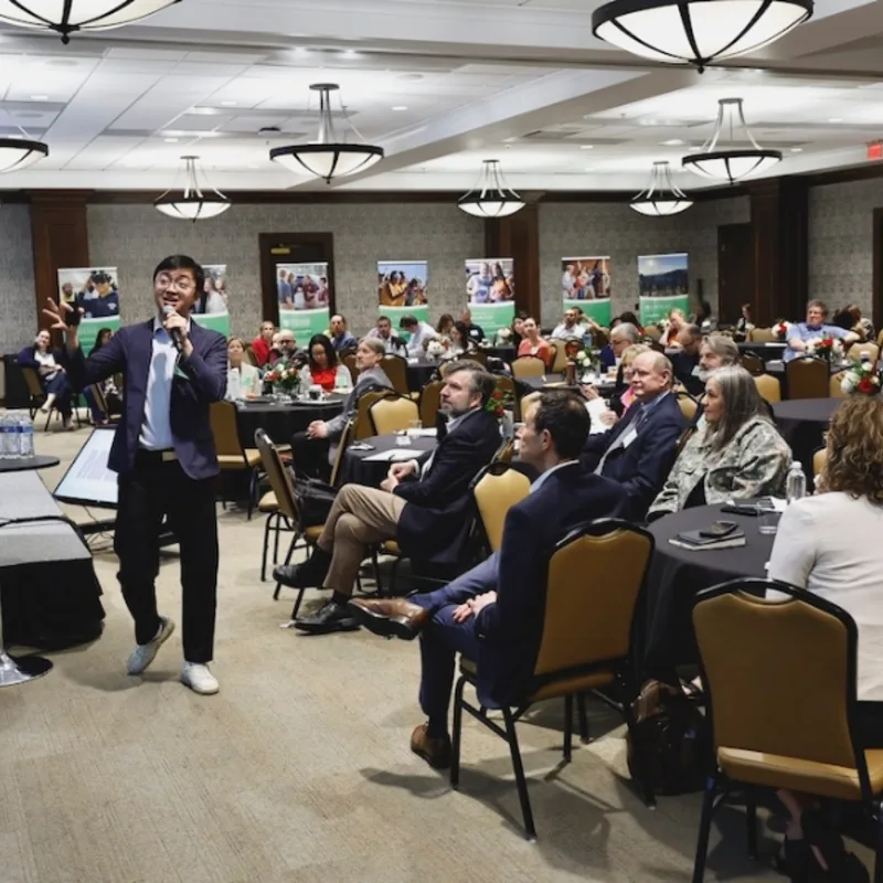 LearningWell Conference attendees; presenter speaking, gesturing with hand in front of crowd