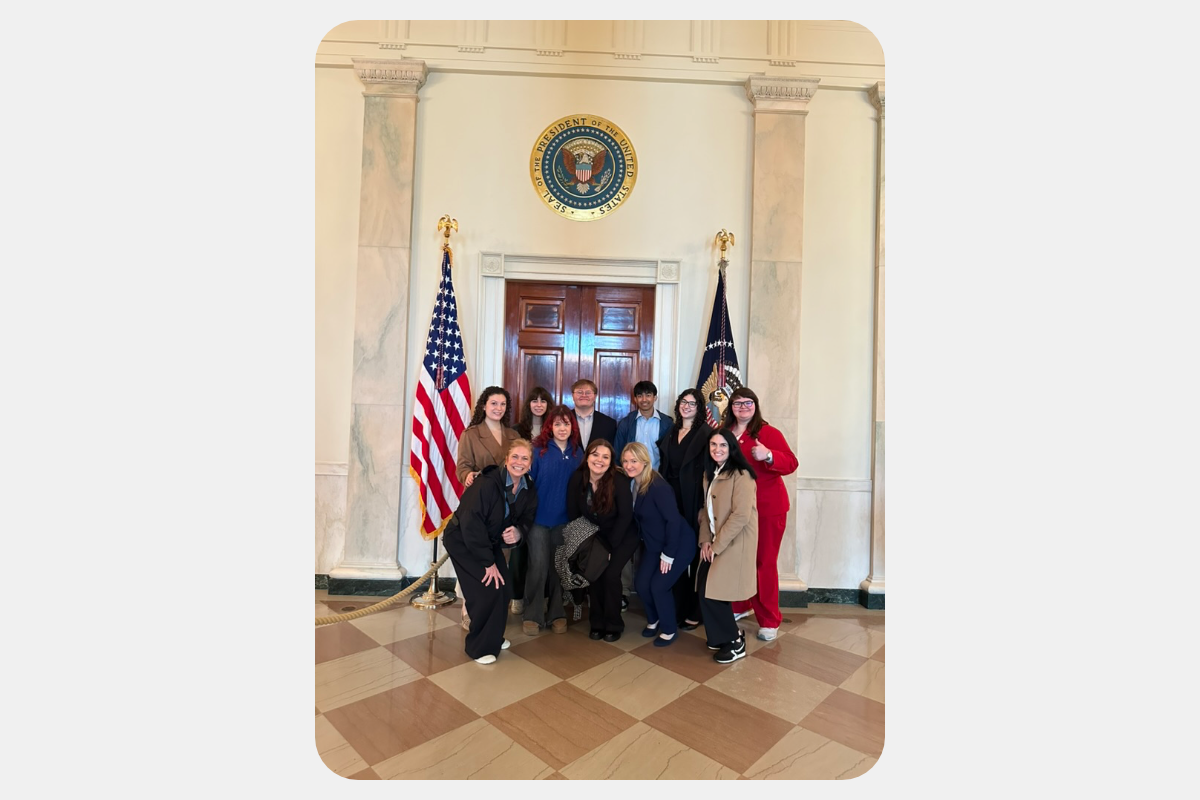 Group photo at the White House, with the Presidential Seal and American flag in the background.