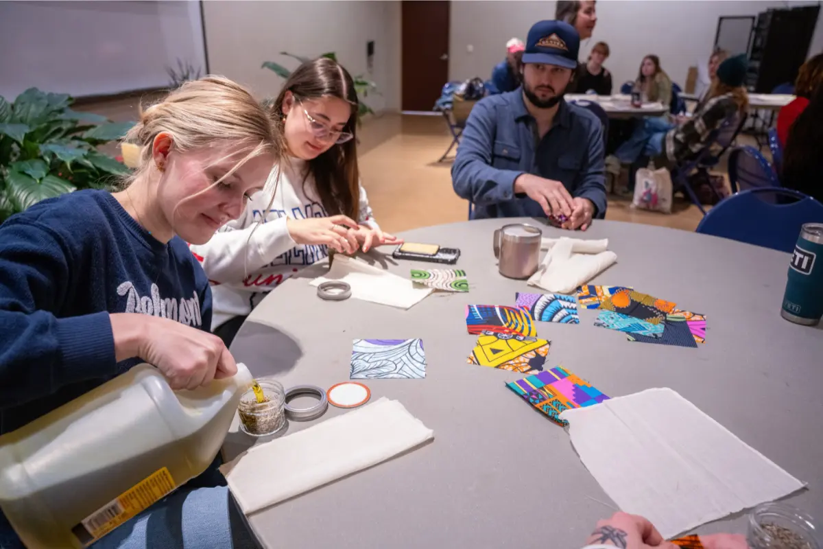 Belmont students students gather around a table making lavender essential oil during a workshop