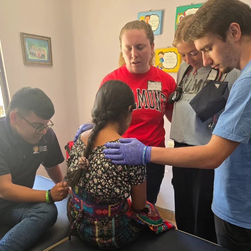Students praying for a woman in a Guatemalan clinic