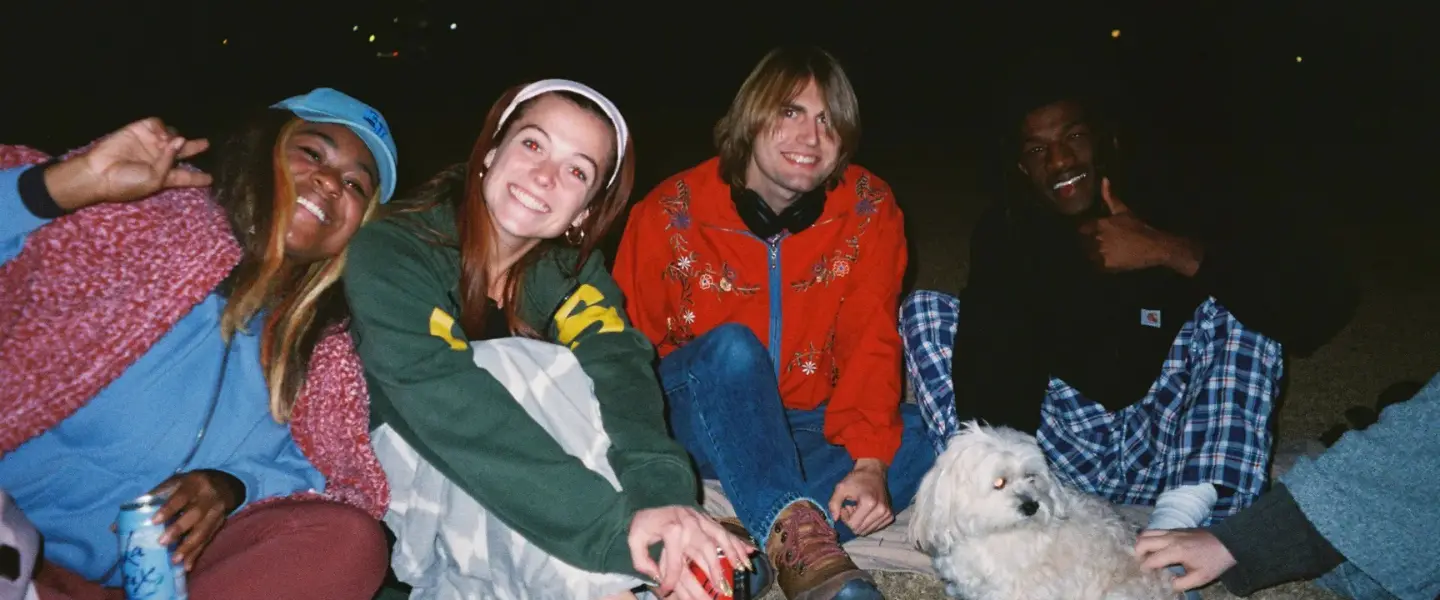 students sitting together on lawn with puppy 