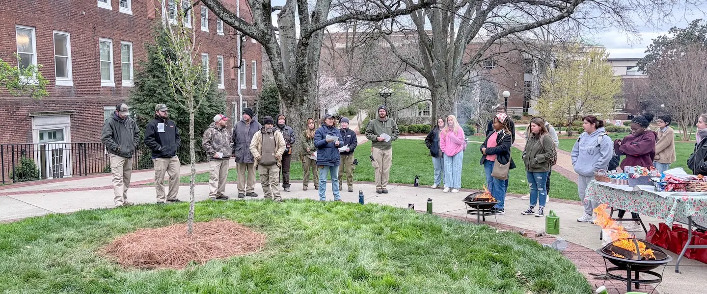 Group of people standing around newly planted tree