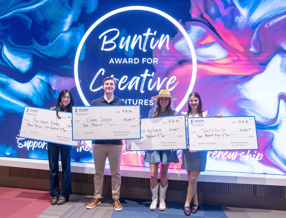 Four students holding big checks