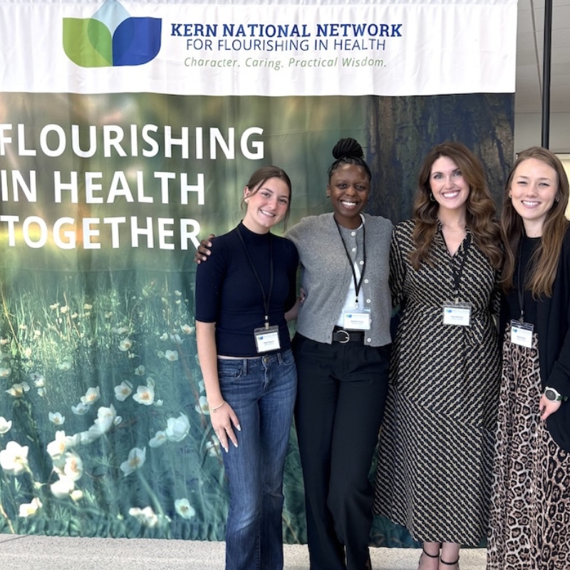Four students pose in front of KNN banner
