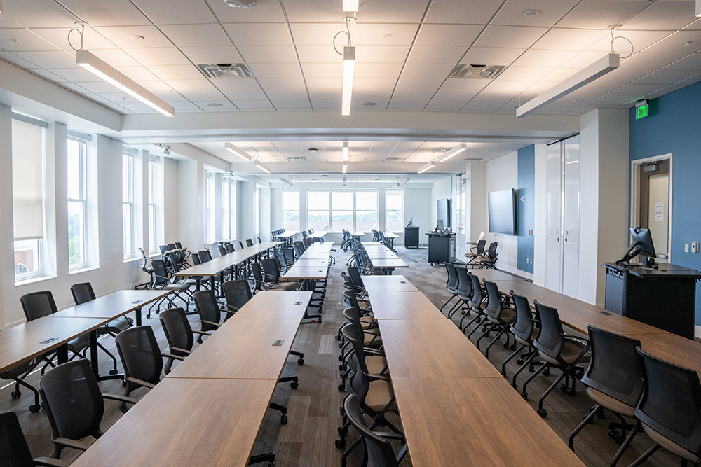 Hackathon classroom full of tables and chairs set up classroom style.