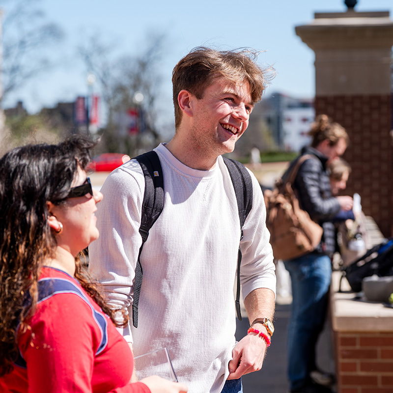 Groups of students laughing together in a circle outside on a sunny day