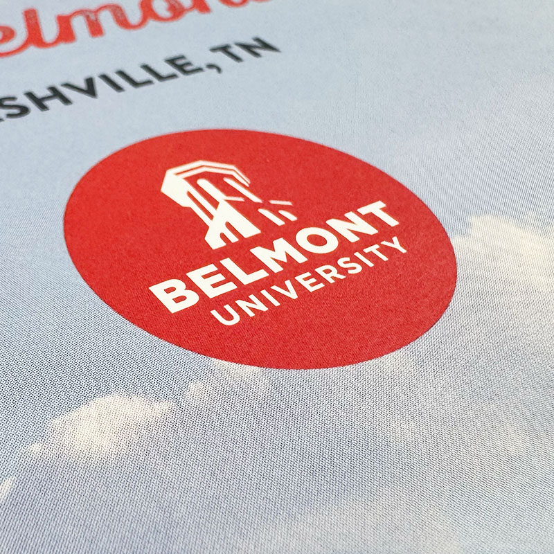 Close-up of a Belmont University logo printed on a textured surface, featuring a red circle with the university's name and an emblem inside.