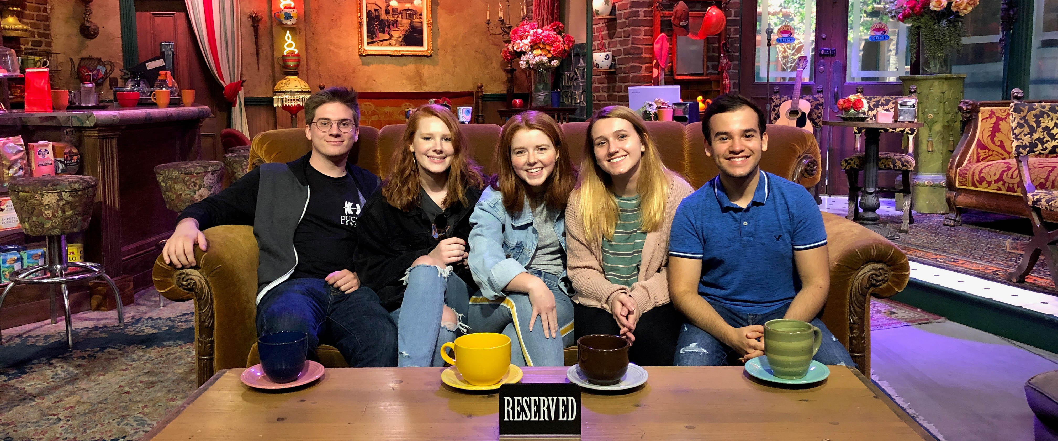 Belmont USA students pose on the couch in the coffee shop from the set of Friends