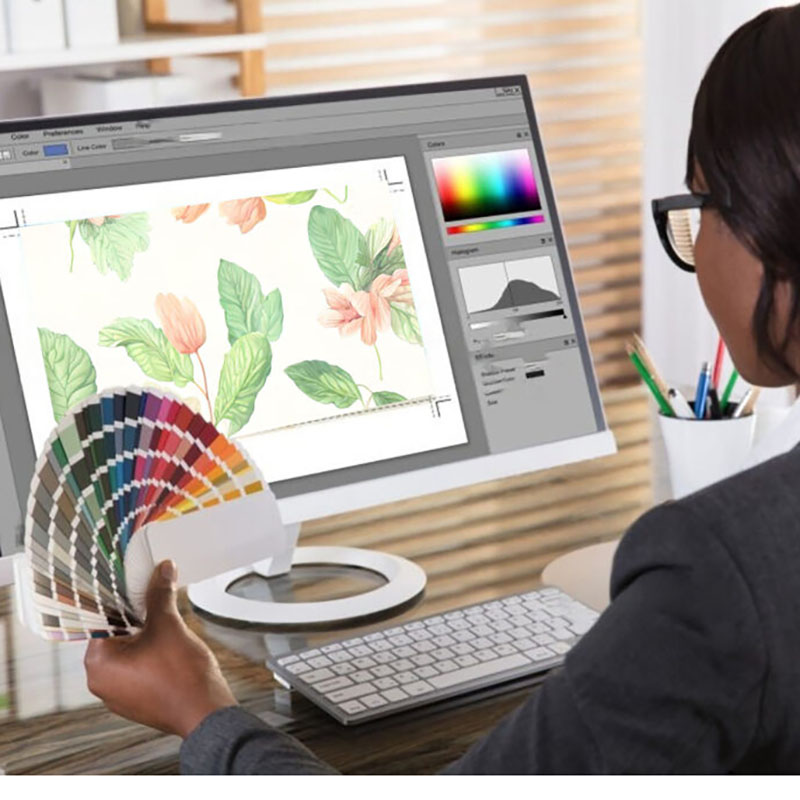 A student references color swatches while on the computer, graphically designing.