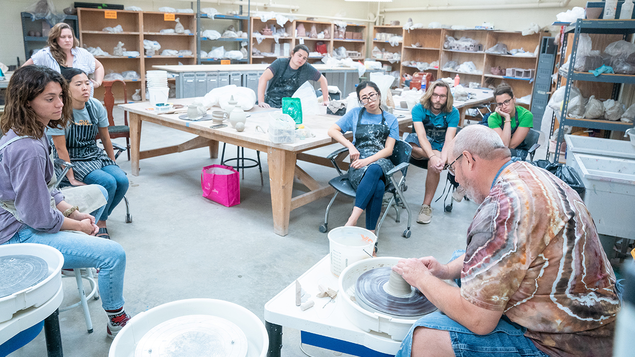 Students watching a clay demonstration on the potter's wheel.