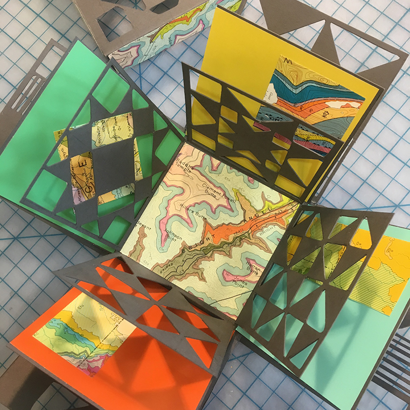 close up image of an opened box with decorative embellishments of maps and quilt square patterns